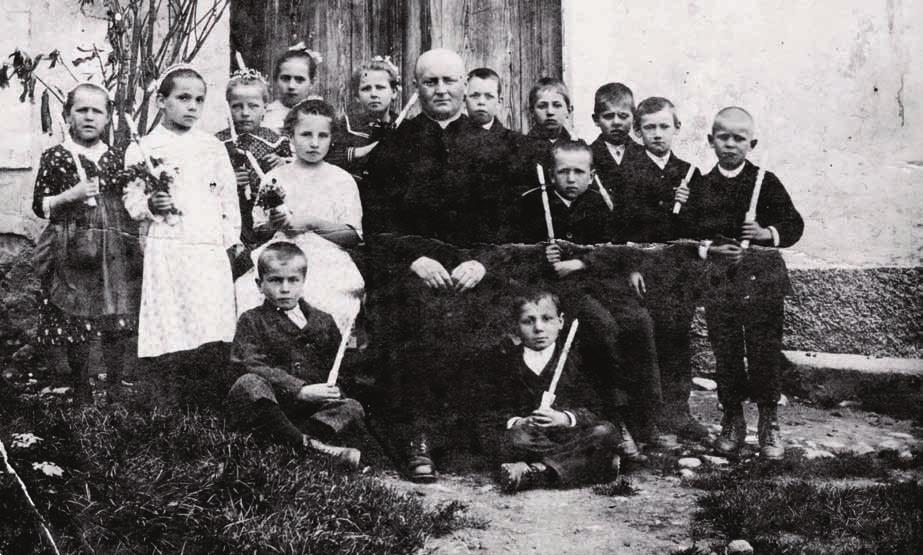 obhajilo leta 1922. 14 otrok z æupnikom g. Stichom pred farovæem.