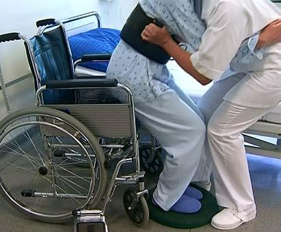 Slika 13: Premeščanje oskrbovanca na invalidski voziček s pasom in vrtljivim krožnikom Premeščanje oskrbovanca s postelje na transportni voziček Pri premeščanju oskrbovanca na transportni voziček je