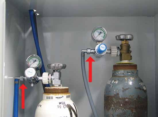 Slika 2: Osrednja preskrbovalna enota kisika in dušikovega oksidula. Puščici prikazujeta plinski spojki, ki povezujeta jeklenki s cevmi plinske napeljave.