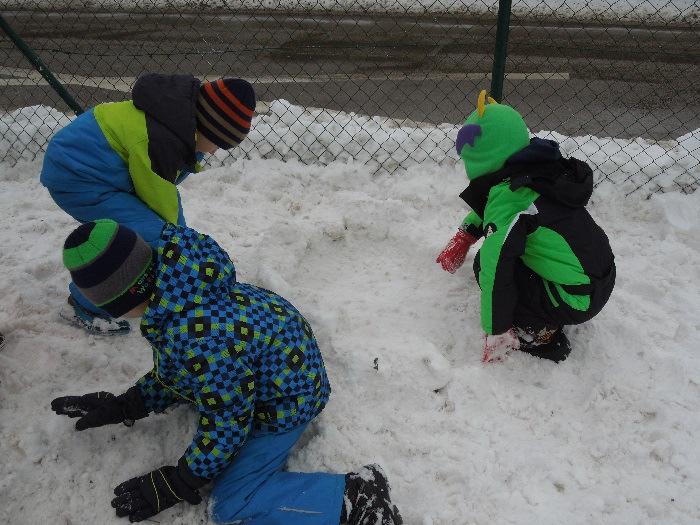 Otroci iz pomrznjenega snega oblikujejo kocke in jih zlagajo eno na drugo v obliko manjšega igluja. Otroci iz kupa snega s pomočjo lopat oblikujejo snežena bitja in snežake.